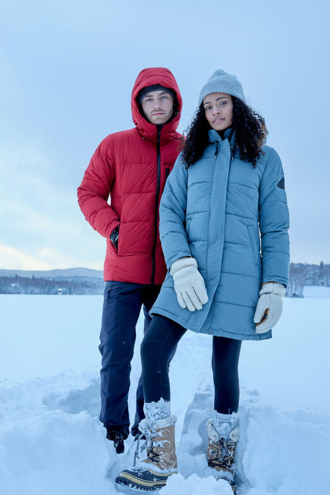 Two people in winter clothing standing on a snow-covered landscape.