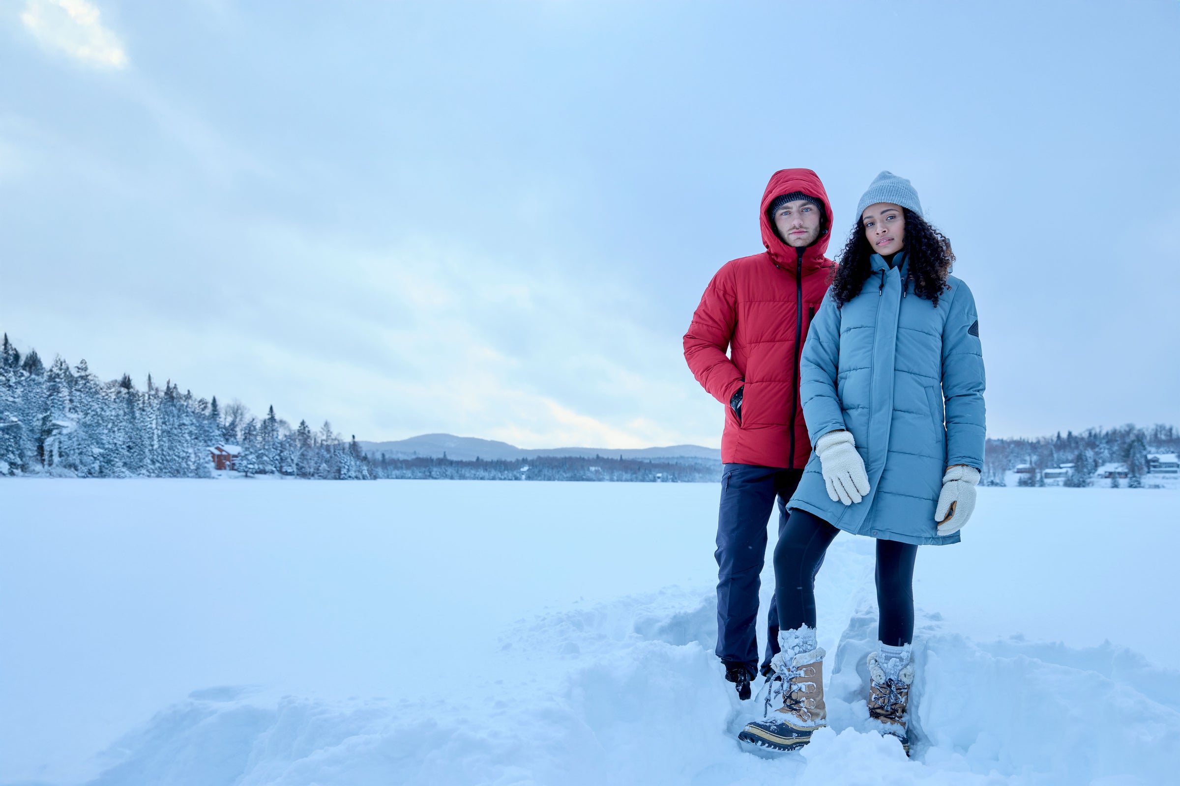 Two people standing on a snow-covered landscape with a clear sky.
